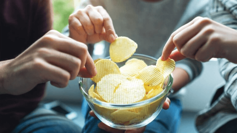 Hands taking chips from bowl